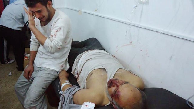 In this undated citizen journalism image provided by the Local Coordination Committees in Syria and accessed on Wednesday, Feb. 8, 2012, a man weeps as he sits next to a man who was purportedly killed in shelling by Syrian government forces, Homs, Syria. 