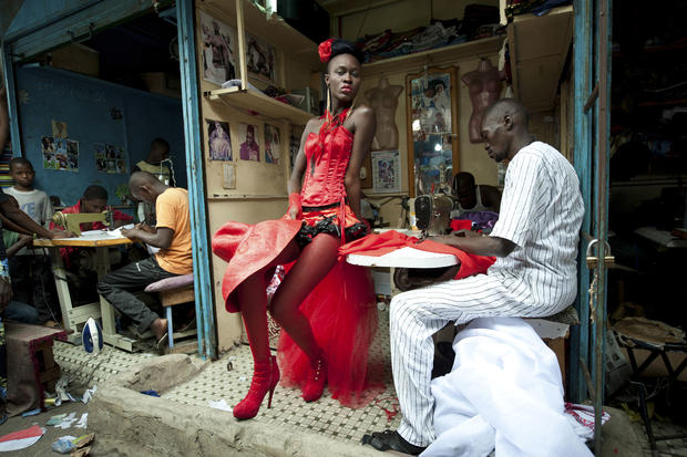 Riva Press for Le Figaro Magazine, shows a model posing in front of tailor stalls in the center of Dakar 