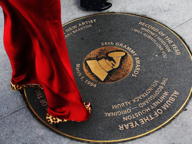 A woman arriving for tonight's Grammy awards looks at a Grammy sidewalk plaque, honoring Whitney Houston's 