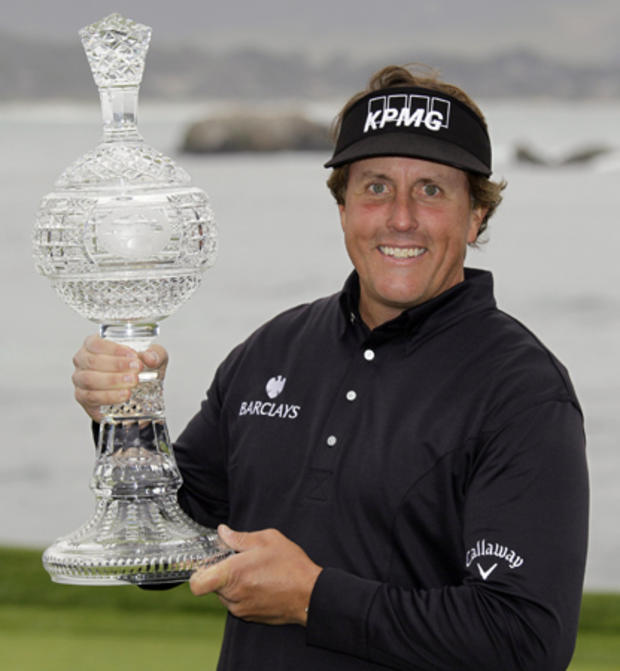 Phil Mickelson holds his trophy on the 18th green of the Pebble Beach Golf Links  