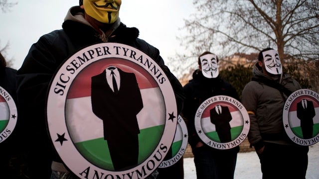Protesters wearing Guy Fawks masks hold the logos of the international hacker group Anonymous during a demonstration against Anti-Counterfeiting Trade Agreement in Budapest, Hungary, Feb. 11, 2012. 