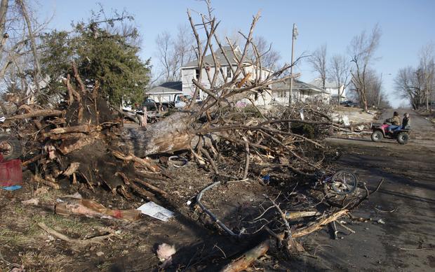Residents ride past a tree that was downed by severe storms that destroyed several homes 