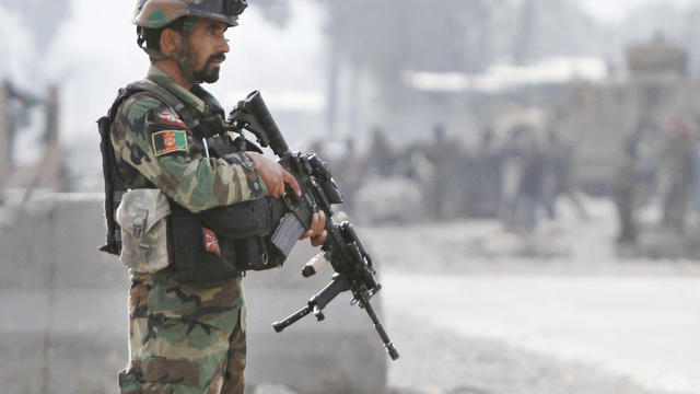 Afghan soldier stands guard at the scene of a suicide attack at the gate of an airport in Jalalabad 