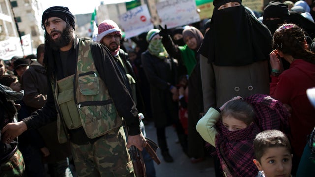 A Free Syrian Army fighter stands among protesters during an anti government protest in a town in north Syria, March 2, 2012.  