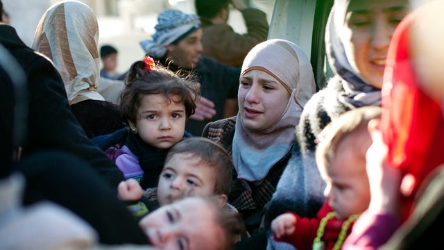 A family leaves their house after the building was hit by a Syrian Army tank in Idlib, Syria, March 4, 2012. 