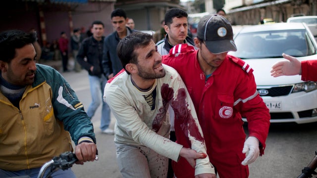 Medics help a wounded man outside a hospital during fighting between Syrian rebels and government forces in Idlib, Syria, March 11, 2012. 