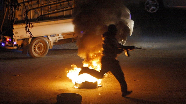 Syrian rebel runs with his AK-47 towards a Syrian army checkpoint in a suburb of Damascus 