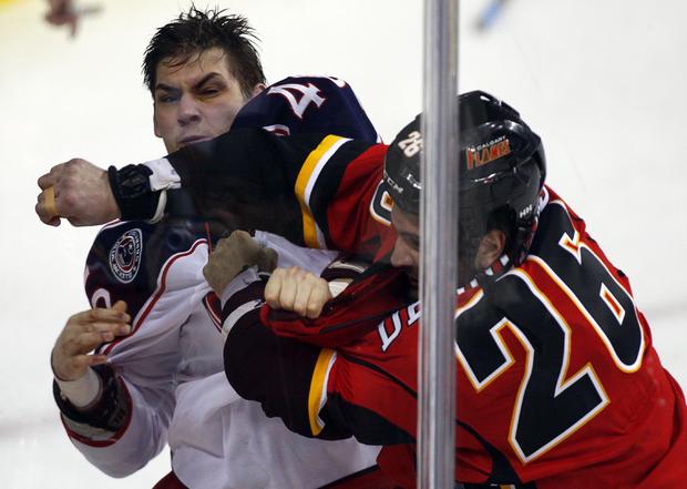 Columbus Blue Jackets' Jared Boll, left, fights with Calgary Flames' Guillaume Desbiens  