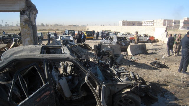 People and security forces inspect the scene of a car bomb attack in Kirkuk, 180 miles north of Baghdad, Iraq, March 20, 2012.  