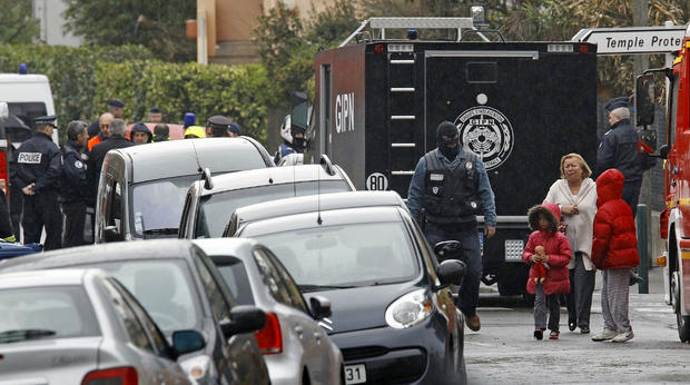 A woman and children are escorted by a police officer near a building where the chief suspect in a killing spree is holed up in an apartment in Toulouse, France, March 22, 2012. 
