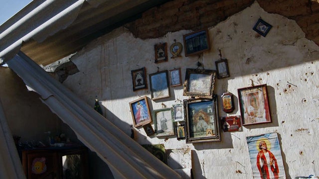 A piece of metal sheeting hangs from the roof of a home damaged by a magnitude-7.4 earthquake  