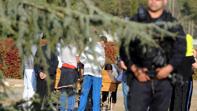 A policeman stands guard as relatives of Islamist extremist Mohamed Merah attend the burial of his body March 29, 2012, in the Muslim unit of the cemetery in the Cornebarrieu neighborhood of Toulouse, France. 