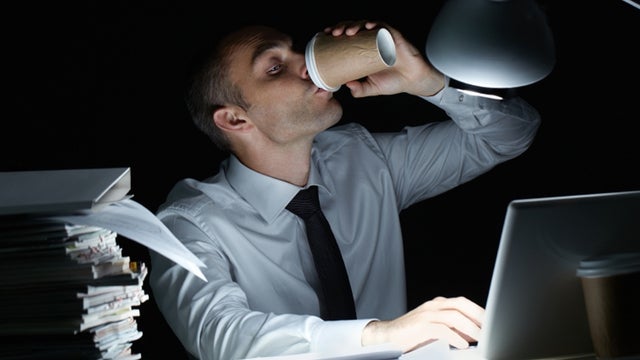 Manager working in office at night and drinking coffee at his workplace 