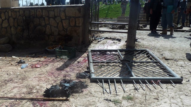 Afghan policemen inspect the site of a suicide attack 