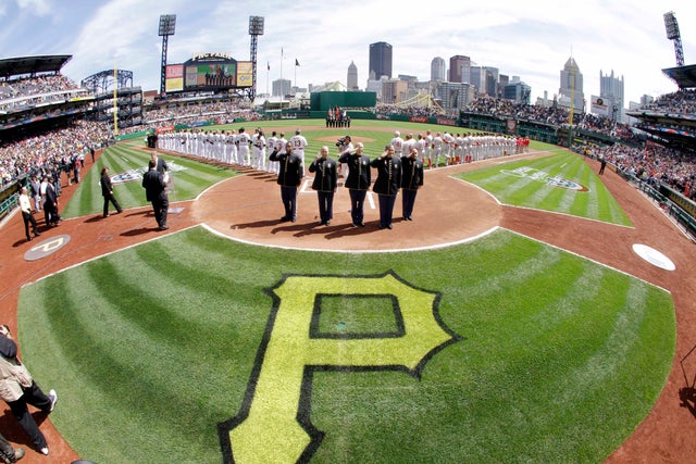 members of a military group salute after singing the national anthem before the start of an opening day 