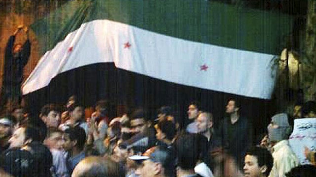 In this image provided by the Local Coordination Committees in Syria and made available on Tuesday, April 10, 2012, Syrians hold the Syrian revolutionary flag aloft during a demonstration in Damascus, Syria.  