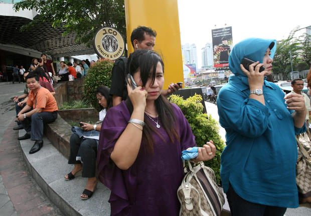 Indonesian women make phone calls as they are evacuated from a shopping mall  