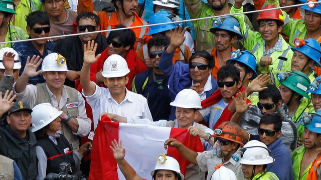 Peru's President Ollanta Humala, stands with nine rescued miners, wearing sunglasses, after they were freed from the Cabeza de Negro gold-and-copper mine in Yauca del Rosario, Peru, April 11, 2012.  