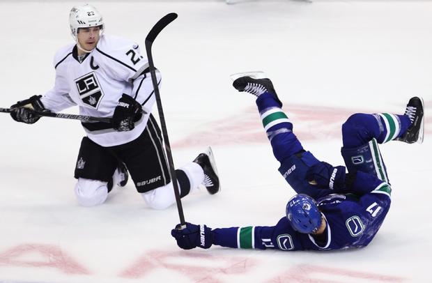 Ryan Kesler falls to the ice after a collision with Dustin Brown  