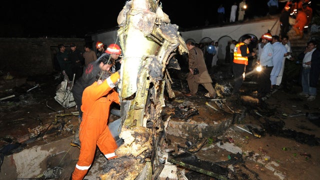 rescue workers and local residents search the site of a plane crash  