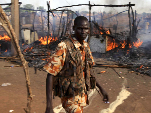 A policeman walks past the smouldering remains of a market in Rubkona, South Sudan, April 23, 2012. 