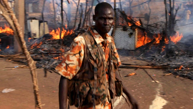 A policeman walks past the smouldering remains of a market in Rubkona, South Sudan, April 23, 2012. 