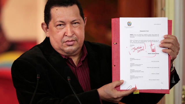 Venezuela's President Hugo Chavez shows a copy of a new labor law he just signed during a T.V. broadcast in Caracas, Venezuela, April 30. 2012. 