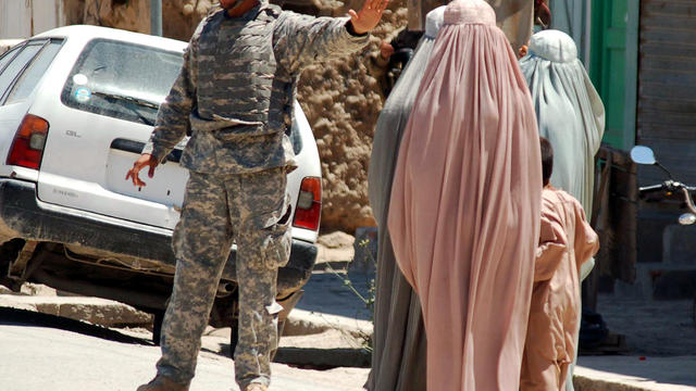 A U.S. soldier stops Afghan women from walking toward the vicinity of the governor's compound in Kandahar, Afghanistan, April 28, 2012. 