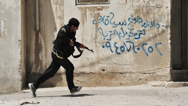Syrian rebel runs for cover at the Sunni district of Jabb al-Jandali in Homs 