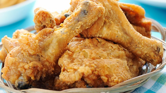 Basket of crispy fried chicken with fries out of focus on a blue background. 
