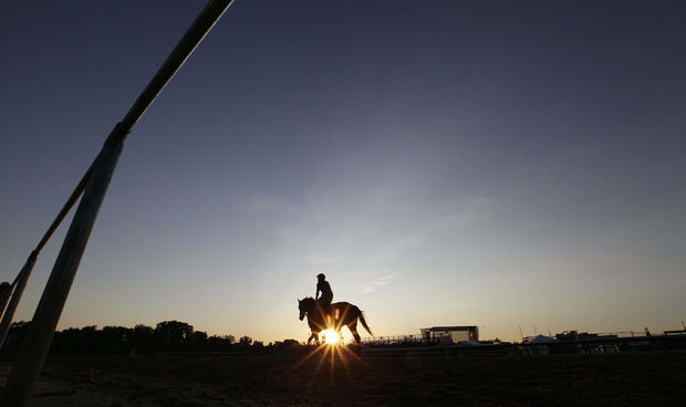 The sun rises as a rider heads to a morning workout at Pimlico Race Course 