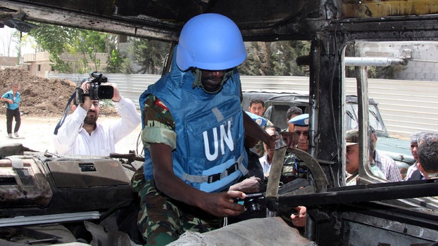 A U.N. observer takes pictures of a military bus that was damaged by a roadside bomb in the al-Bahdaliyah area near Damascus, Syria, May 23, 2012. 