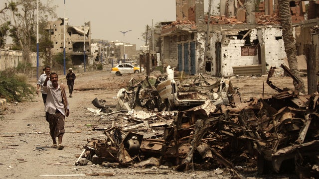 Yemeni man walks past cars destroyed during fighting with al Qaeda militants 