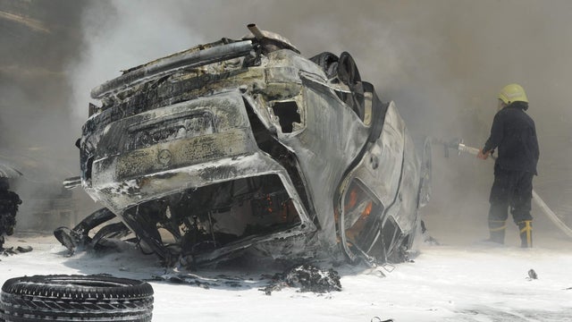 fireman tries to extinguish fires at the scene of two huge bomb explosions outside the Palace of Justice in Central Damascus 