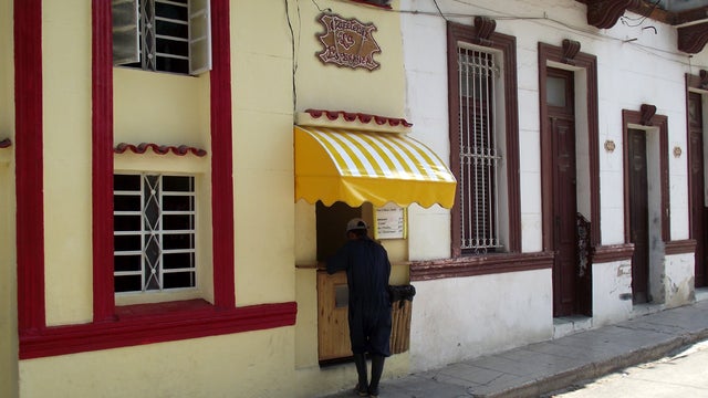 A customer picks up take-out food sold out of a private home's front door in Havana. 