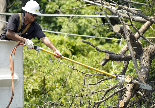 A utility worker clears a downed tree from power lines 