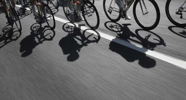 Riders cast shadows on the road during the first stage of the Tour de France 