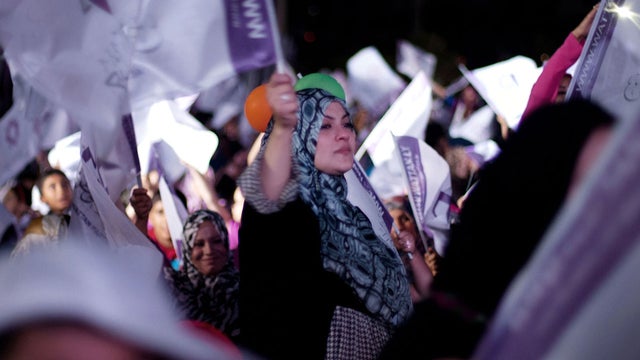 In this Wednesday, July 4, 2012 photo, a Libyan woman waves the Al Wattan Party flag during a rally at the seaport of Tripoli, Libya. The Libyan National Assembly elections will take place on July 7, 2012. It will be the first free elections since 1969.  