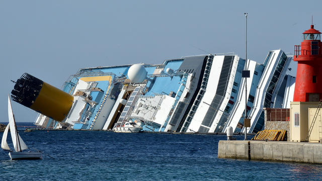 A small dinghy sails past the stranded Costa Concordia cruise ship near the harbor of Giglio Porto June 25, 2012, in Italy. 
