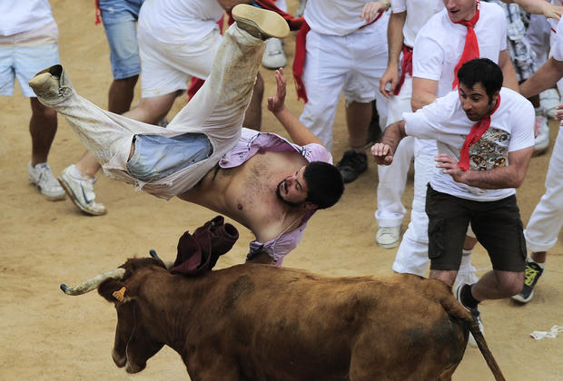 A reveler is tossed by a bull in the bull ring 