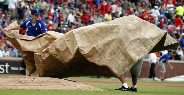 Wind blows the tarp as the grounds crew struggles to cover the mound  