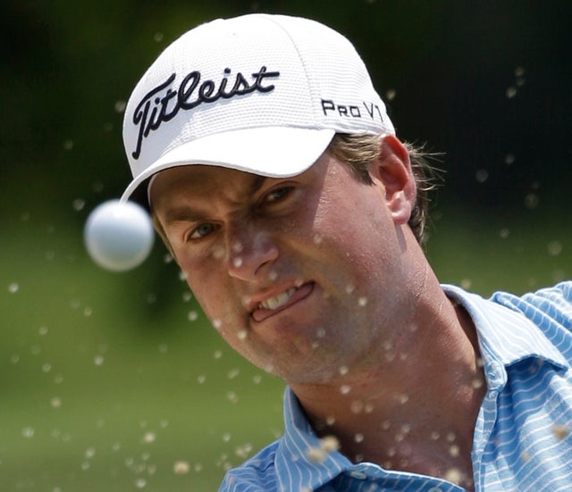Webb Simpson watches the ball as he hits out of a bunker 