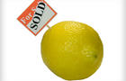 A whole lemon with a for sale and sold sign. 