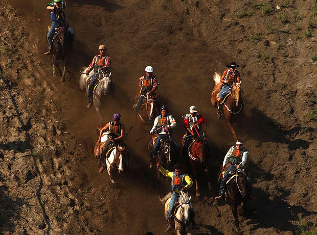 Participants in the Omak Suicide Race ride down a 62-degree slope to the Okanogan River August 15, 2004 in Omak, Washington. 