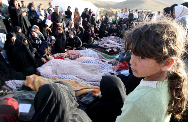 An Iranian girl mourns over the covered bodies of loved ones in Bajebaj village 