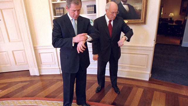 President George W. Bush and Vice President Dick Cheney look at their watches Jan. 26, 2001, following the ceremonial swearing-in ceremony for Secretary of State Colin Powell in the Oval Office of the White House in Washington. 
