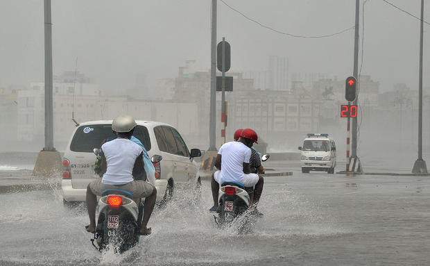 People ride motorbikes in a flooded street in Havana 