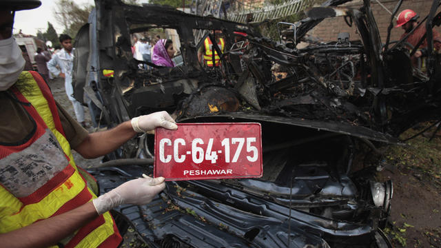 Pakistani worker shows the license plate of the U.S. consulate vehicle hit by a blast in Peshawar 