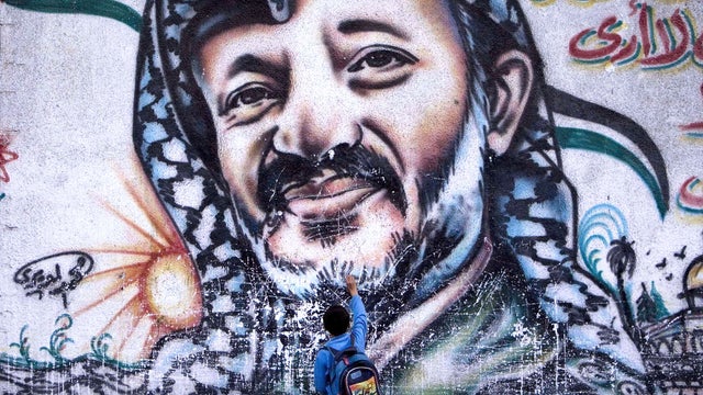 A Palestinian boy touches a mural of the late leader Yasser Arafat, in Gaza City on Nov. 10, 2009. 
