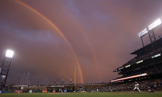 a rainbow appears in the sky during the first inning of a baseball game 